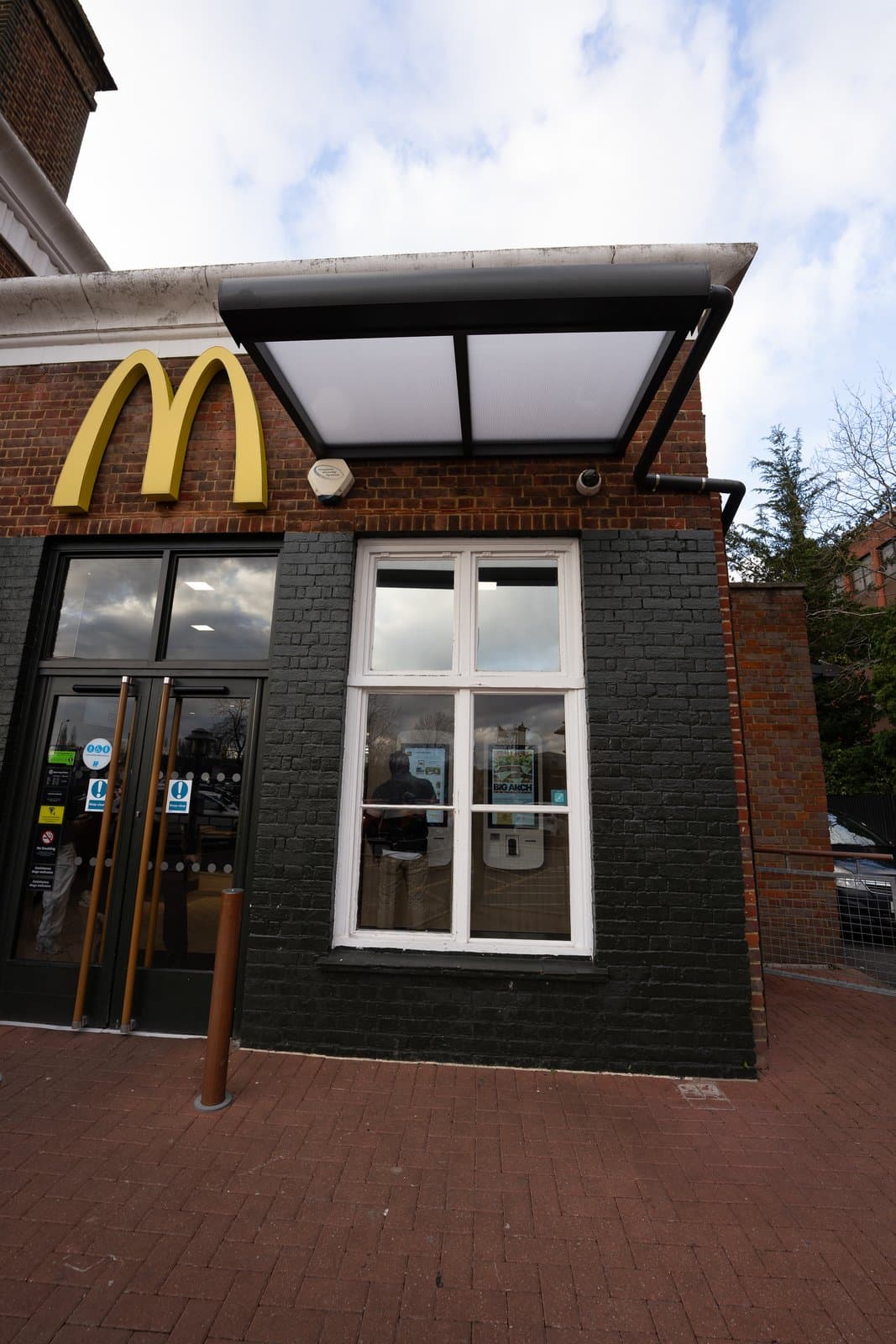 Wall-mounted aluminium veranda canopy shelter over window and entrance at McDonald's in Borehamwood Hertfordshire.