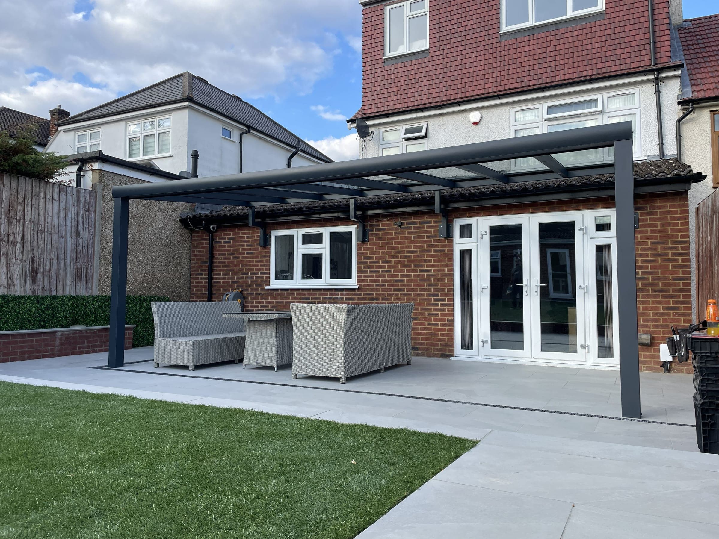 Completed bespoke aluminium veranda installation over paved patio with outdoor furniture set